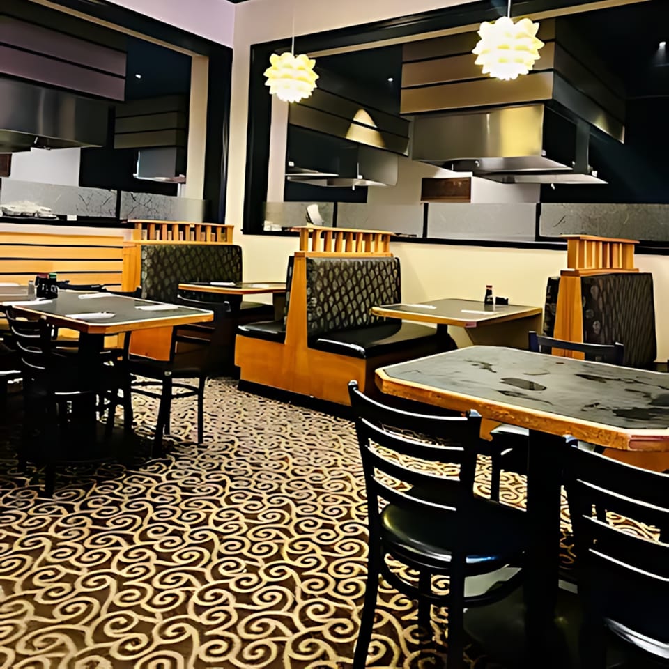 Interior of Sakura Chaya restaurant with empty tables, booths, and a patterned carpet under warm lighting.