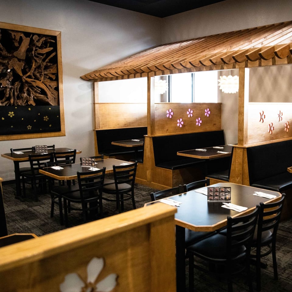 Interior of Sakura Chaya restaurant with wooden booths, tables, chairs, and Japanese-inspired decor.