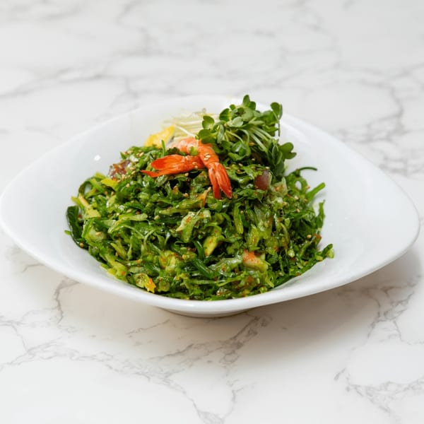 Sakura Chaya's green seaweed salad with shrimp and microgreens in a white bowl.