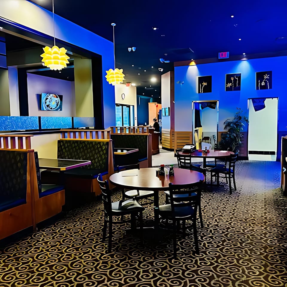 Interior of Sakura Chaya restaurant with blue walls, patterned carpet, and empty tables and booths.