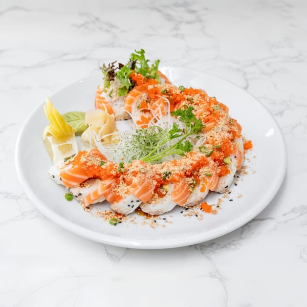 Salmon sushi rolls with orange roe, crushed nuts, and herbs, served with lemon and ginger.