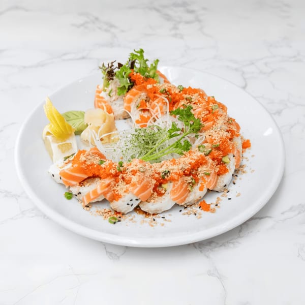 Salmon sushi rolls with orange roe, nuts, and herbs, served with lemon, wasabi, and ginger.